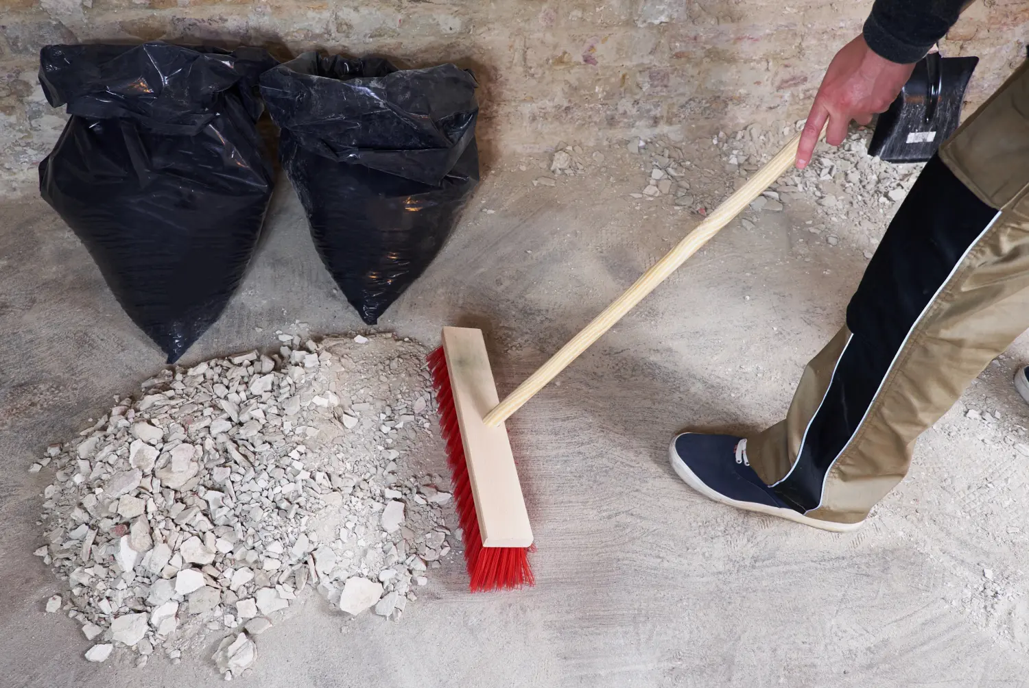Arbeiter, der die Trümmer mit dem Besen kehrt